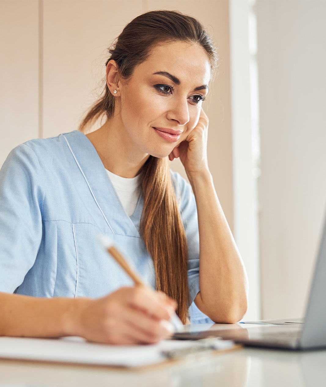 A woman in scrubs taking an online course