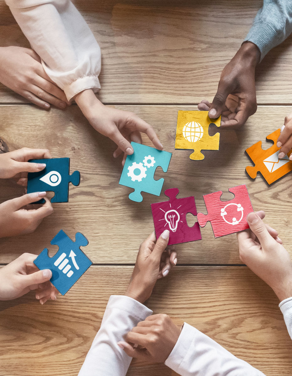 a group of hands placing different color puzzle pieces together